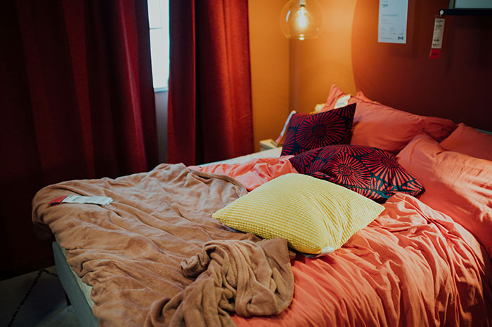 Cozy hotel room with unmade bed, colorful pillows, and warm lighting, illustrating unspoken rules for hotel stays.