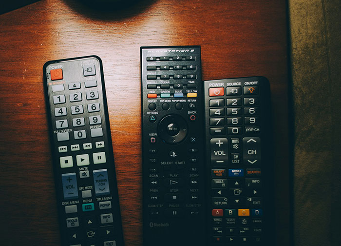 Hotel room remote controls on a wooden table.