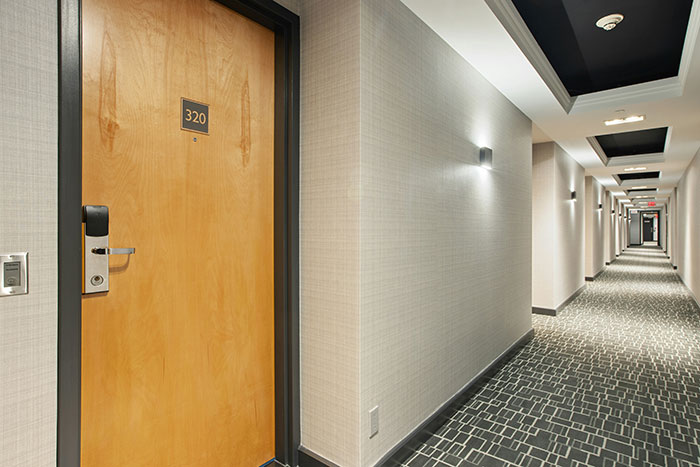 Hotel hallway with room 320, showcasing modern decor and lighting.