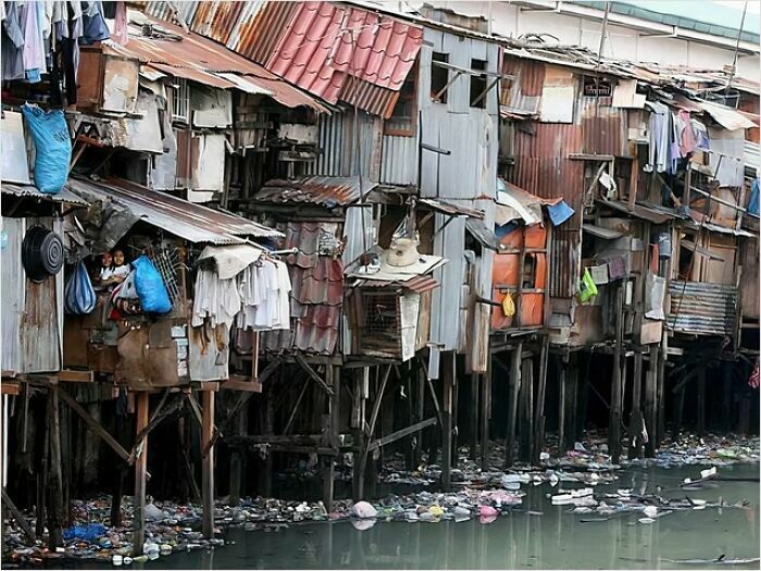 Dilapidated urban structures above polluted water, showcasing urban hell conditions.