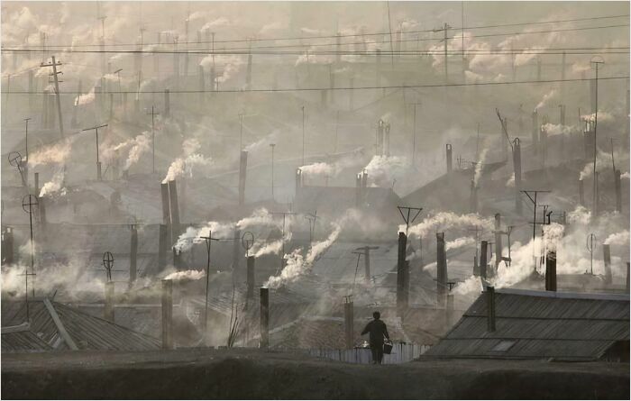 Urban hell scene with dense smog and numerous chimneys releasing smoke, creating an eerie atmosphere.