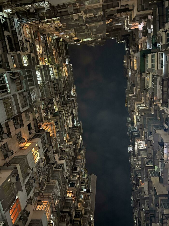 Tall, dense buildings at night form a narrow corridor of urban hell, creating an oppressive atmosphere under the dark sky.