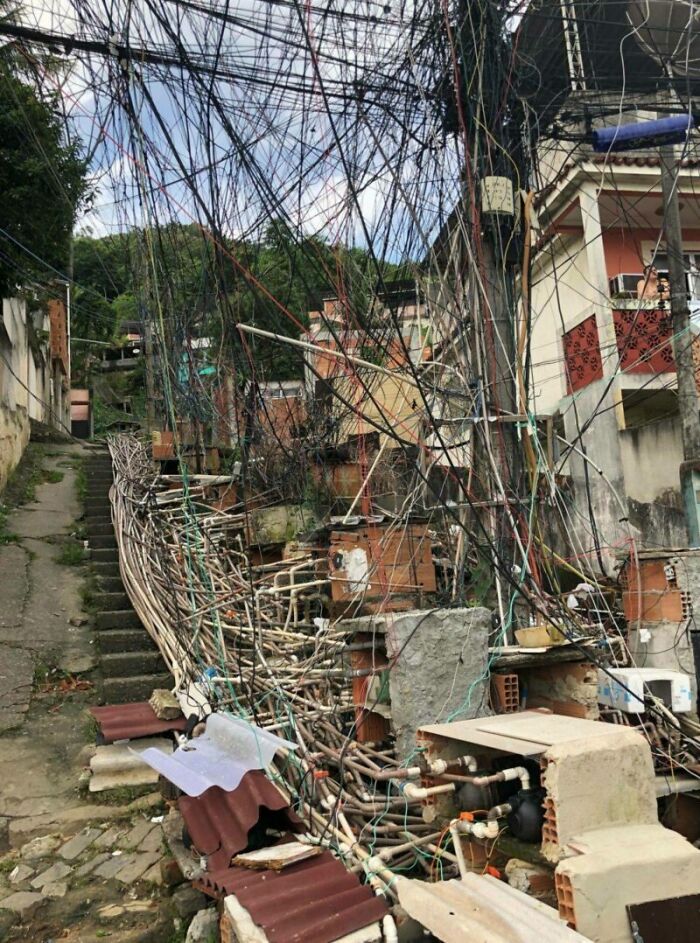 Tangled wires and cables in an urban area, depicting urban hell amidst dilapidated buildings and narrow pathway.