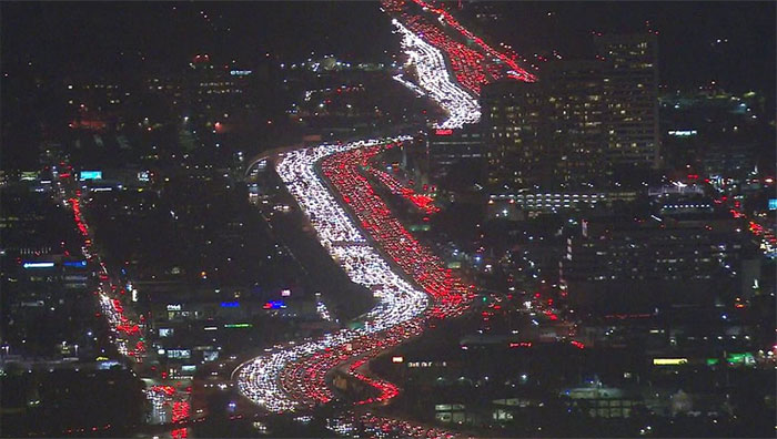 Nighttime urban hell scene with heavy traffic congestion on a city highway, highlighted by red tail lights.