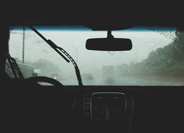 Driving in heavy rain with malfunctioning windshield wipers, illustrating using things wrong way.