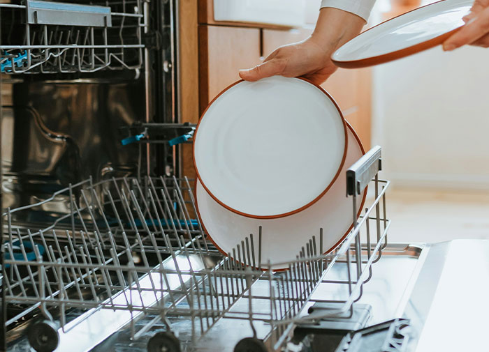 Loading a dishwasher incorrectly with dinner plates, illustrating using-things-wrong-way.