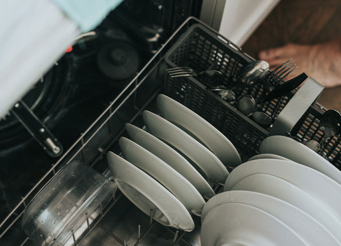 Dishes and utensils arranged incorrectly in a dishwasher, exemplifying using things the wrong way.