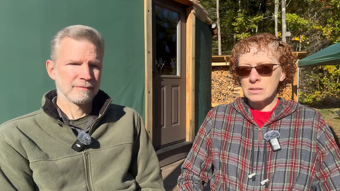 Couple sitting outside their self-built yurt, sharing insights about off-grid living.