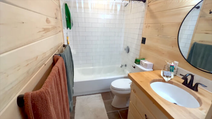 Bathroom in off-grid yurt with wooden walls, a sink, and a bathtub, showcasing sustainable living space details.