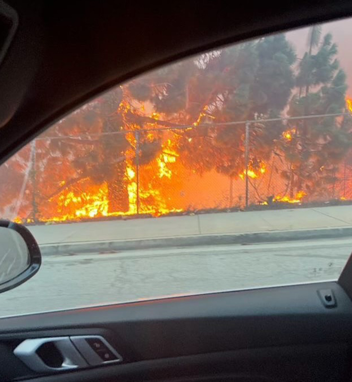 View of LA wildfires through a car window, highlighting the intense flames and impact of celebrities during the crisis.