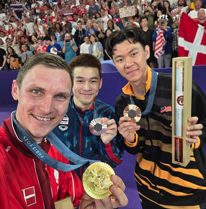 Athletes proudly displaying Paris Olympic medals in a crowded venue.