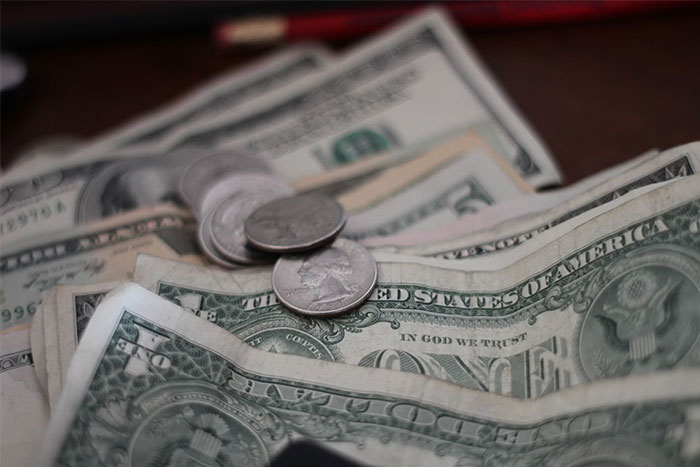 Dollar bills and coins scattered on a table, symbolizing wealth.