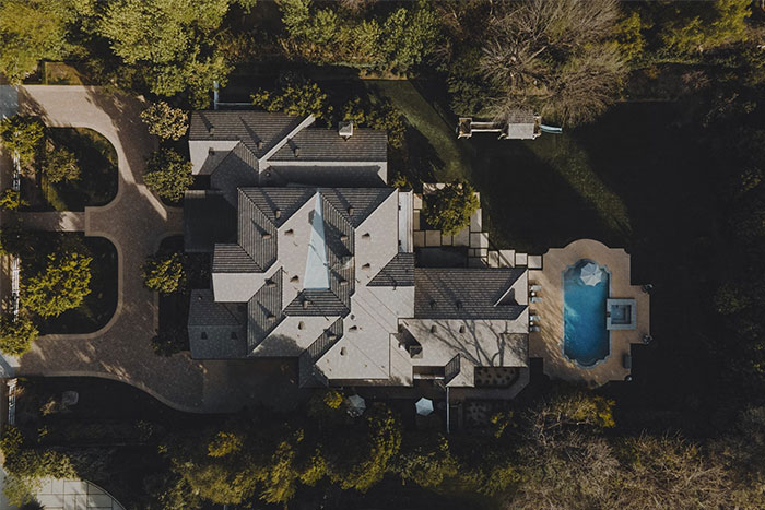 Aerial view of a luxurious estate with a pool, highlighting the wealthy lifestyle protected by bodyguards.