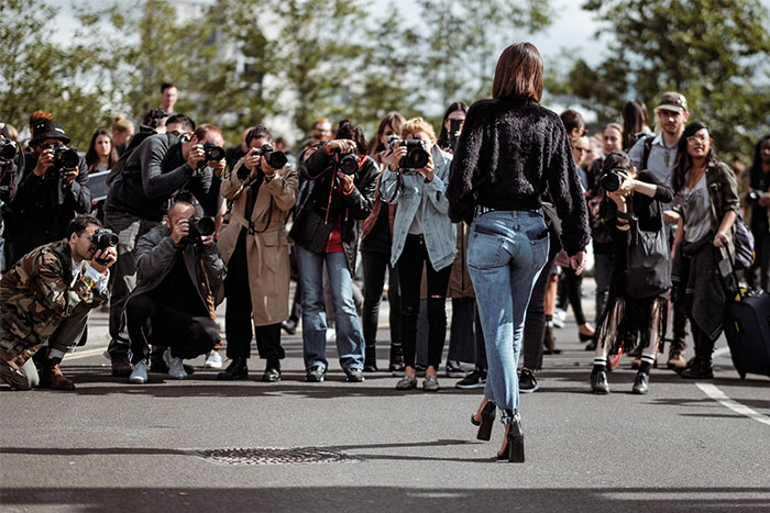 Photographers capturing a woman walking, illustrating the experience of bodyguards for the wealthy.