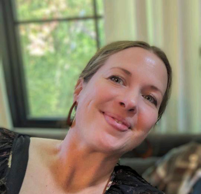 Smiling woman in a soft-lit room, reflecting on past wedding day red flags, near a window.