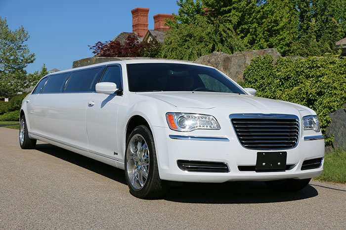 White limousine parked on a suburban street, symbolizing luxury transportation involving rich people.