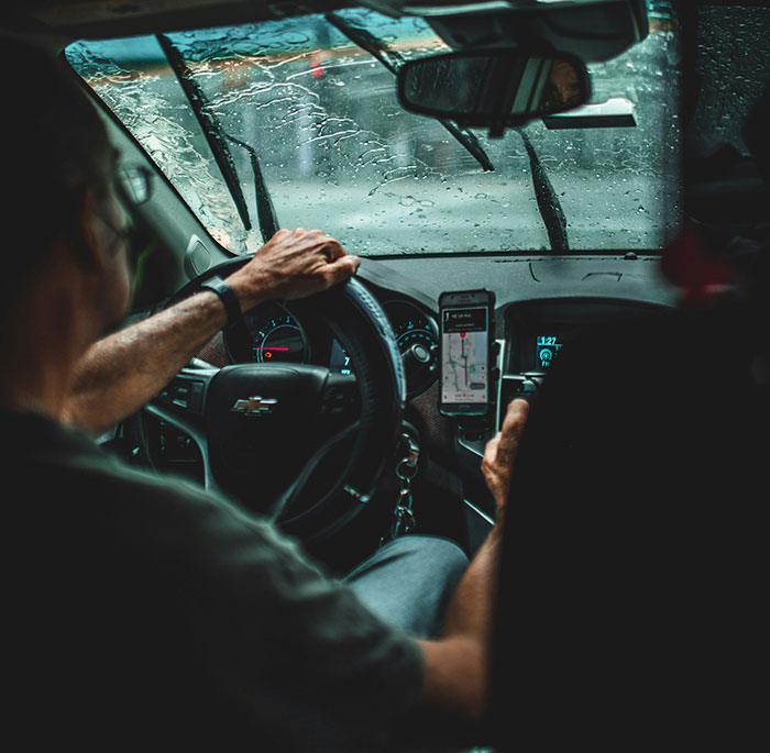 "Driver on a rainy day, navigating while listening to stories about rich people."