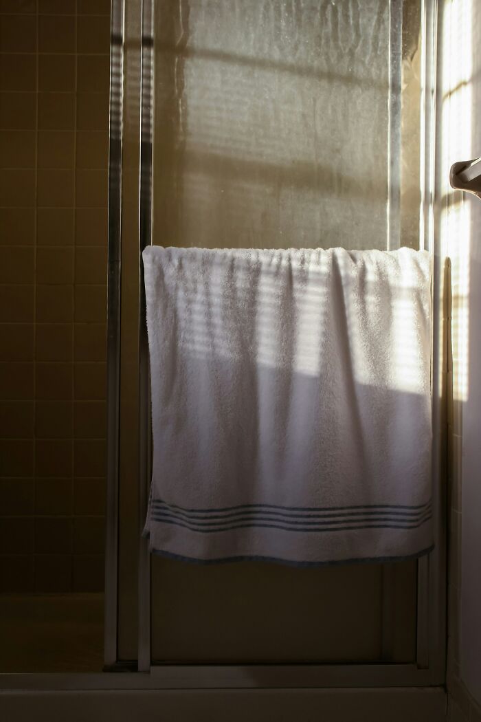 White towel hanging over a glass shower door with sunlight streaming through blinds, illustrating awkward delivery scenario.