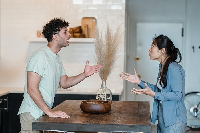 Man and woman arguing in kitchen, highlighting conflict over privacy in pregnancy discussions.