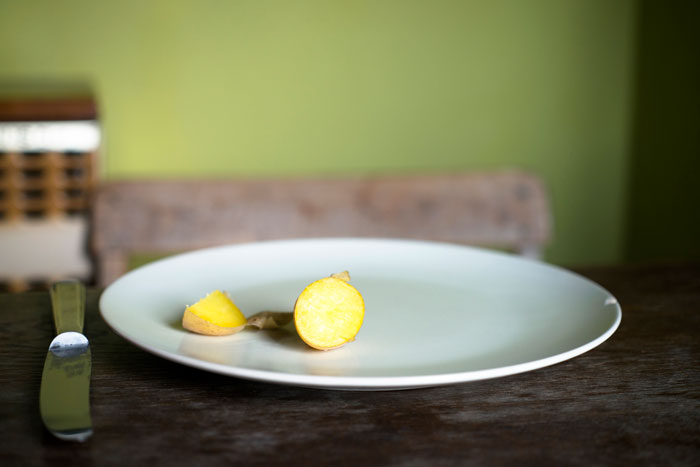 Plate with sliced ginger on a wooden table, emphasizing simplicity and minimalism.