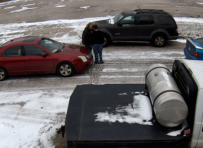 Road rage incident with two people standing between cars on a snowy street.