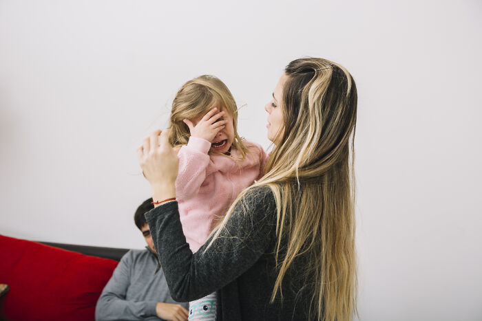 A woman comforts a crying child in a living room, exhibiting human empathy and connection.