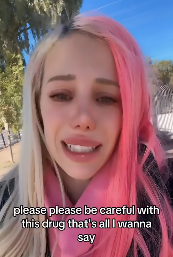 A woman with half pink hair, expressing caution about Ozempic's effects outdoors.