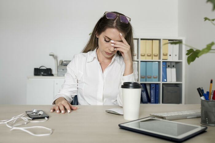 A stressed woman at a desk surrounded by office supplies, highlighting resume red flags in job applications.