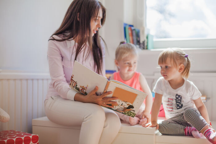 Woman reading a book to two children, showcasing a display of genius in storytelling.