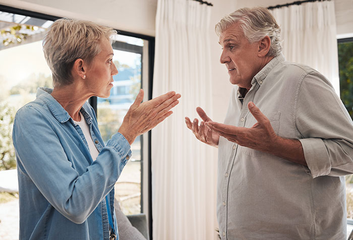 Elderly couple engaged in a tense discussion, reflecting neurodivergent relationship challenges.