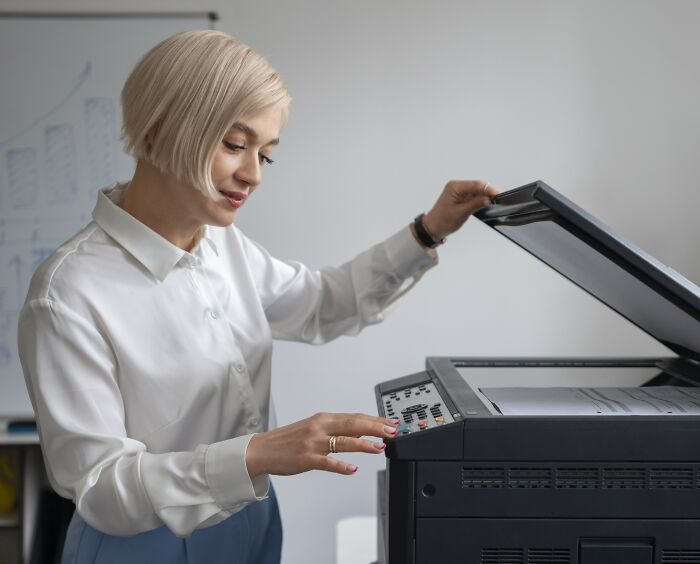 A person using a photocopier in an office setting.