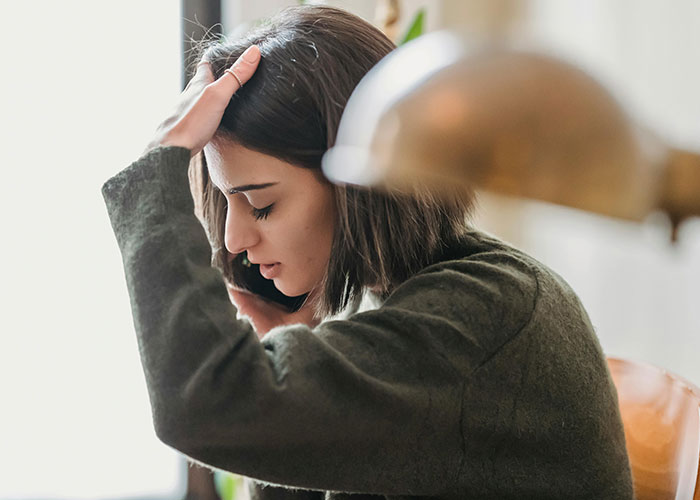 A worried woman on the phone, representing American healthcare issues.