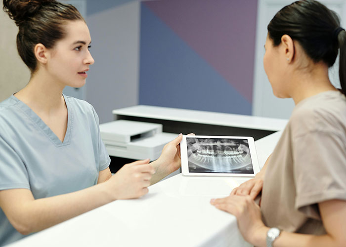 Healthcare worker showing dental X-ray to patient in a clinic setting.