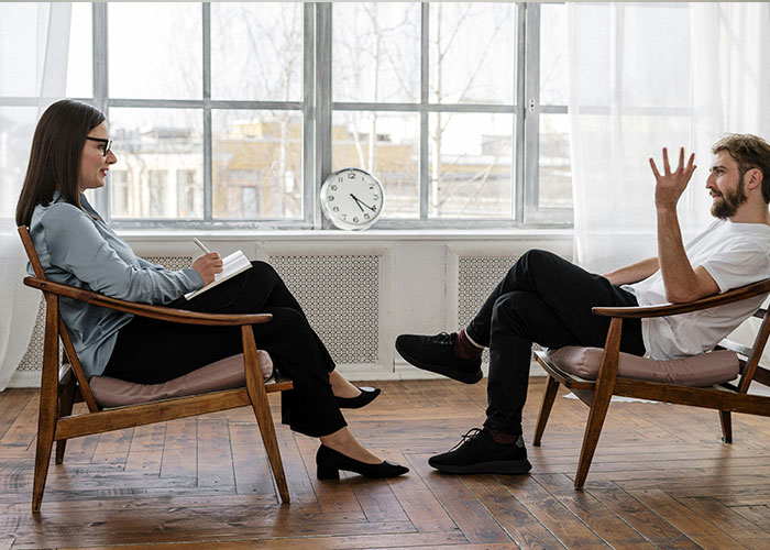 A therapist and patient discussing a difficult experience related to American healthcare in a cozy office setting.