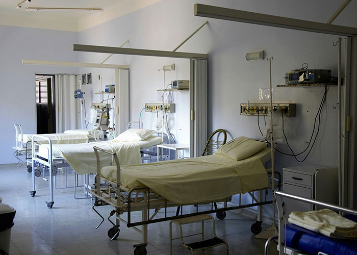 Empty hospital room with multiple beds and medical equipment, illustrating American healthcare challenges.