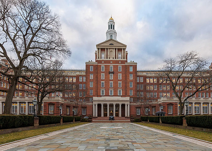 Historic American healthcare building with a central tower, surrounded by leafless trees and a paved walkway.