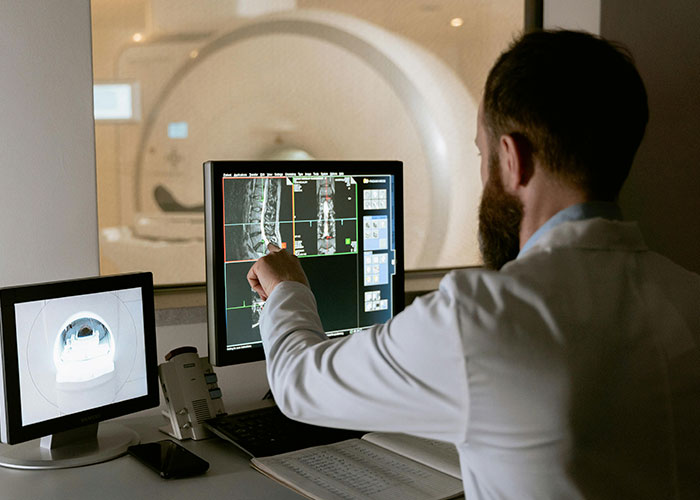 Healthcare professional analyzing MRI scans on monitors.