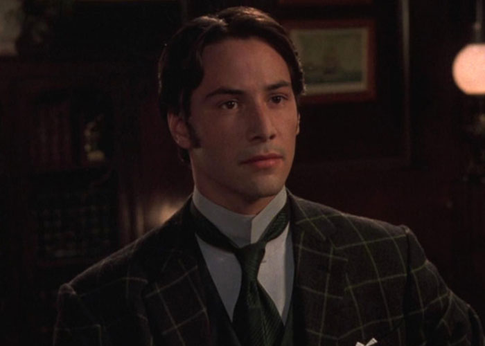 Actor in a period costume, wearing a plaid suit with a contemplative expression, discussed in film snobs' casting critique.