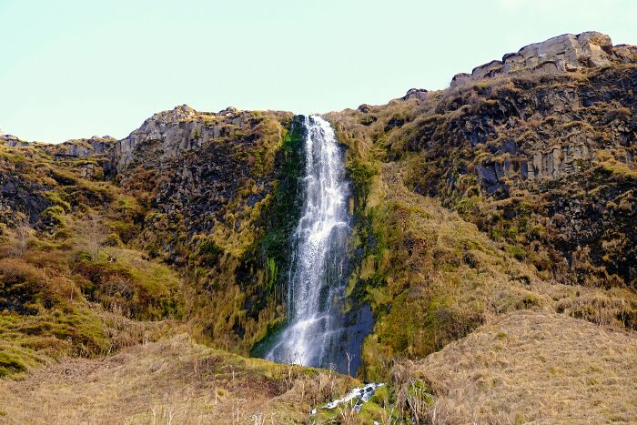 Waterfall in Tuscany, Italy, cascading down rocky cliffs surrounded by lush vegetation.