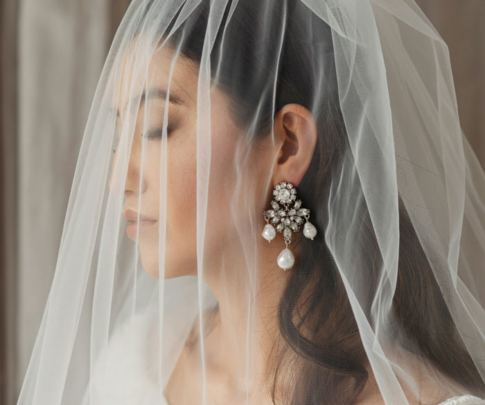 Bride with a veil and pearl earrings, symbolizing a fake wedding revelation.