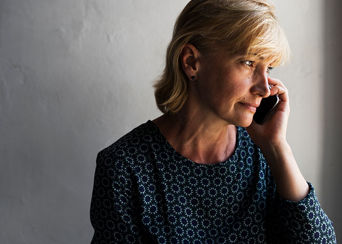 Woman in patterned blouse on phone, looking thoughtful about rent discussions.