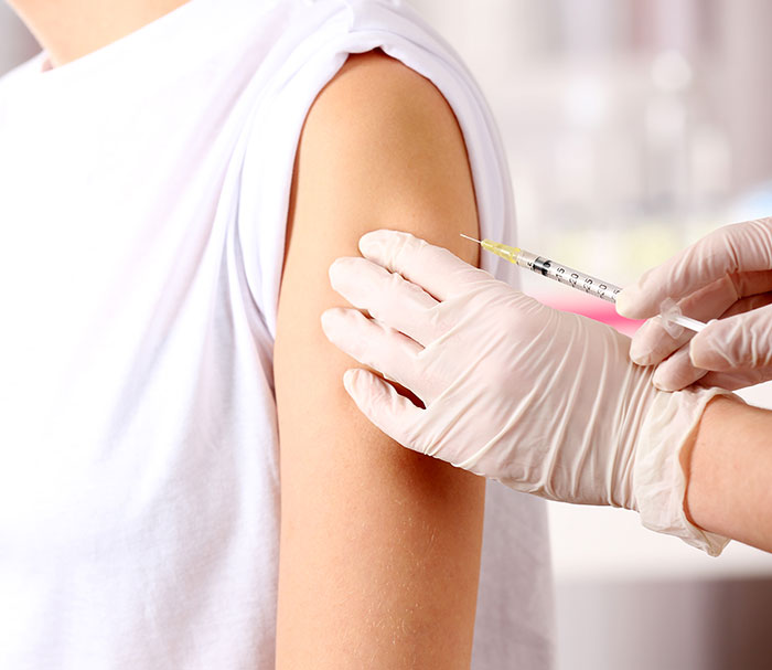 Gloved hands administering Covid vaccine into a person's arm.