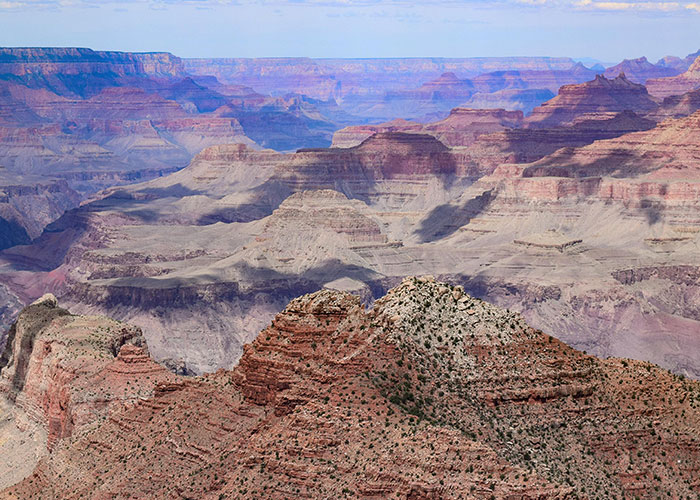 Grand Canyon landscape showcasing layers of rock formations under a clear sky, illustrating wholesome natural beauty.