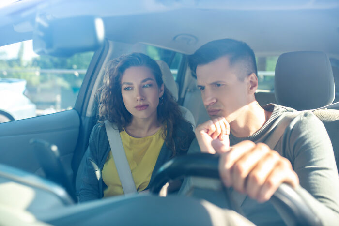 Two people sitting in a car, looking serious, experiencing one of the worst first dates.