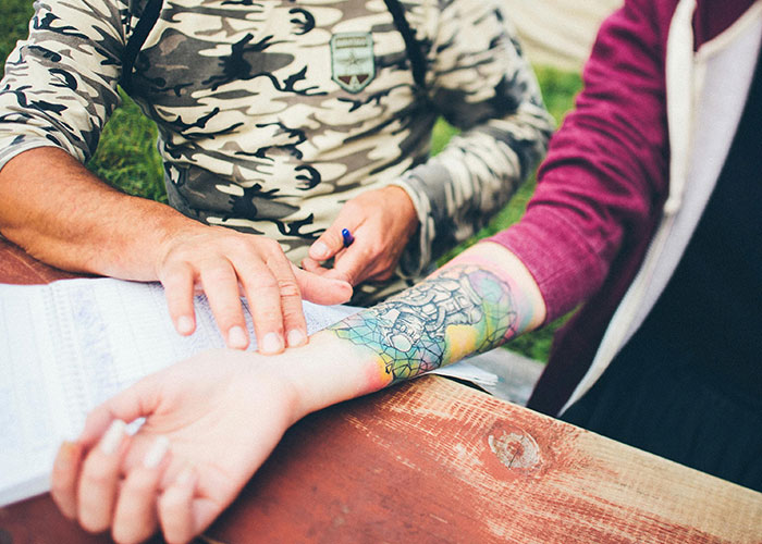 Person with a colorful tattoo on their arm, receiving a consultation outdoors, highlighting things to know before getting inked.