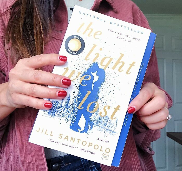 Person holding "The Light We Lost" book, a romantic novel.