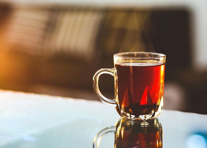 A steaming glass mug of tea on a reflective table, highlighting European culture shocks experienced by some Americans.