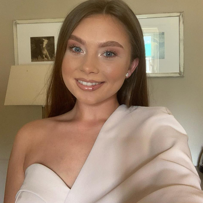 Young woman in a white dress smiling indoors, related to soldier's situation involving text messages.