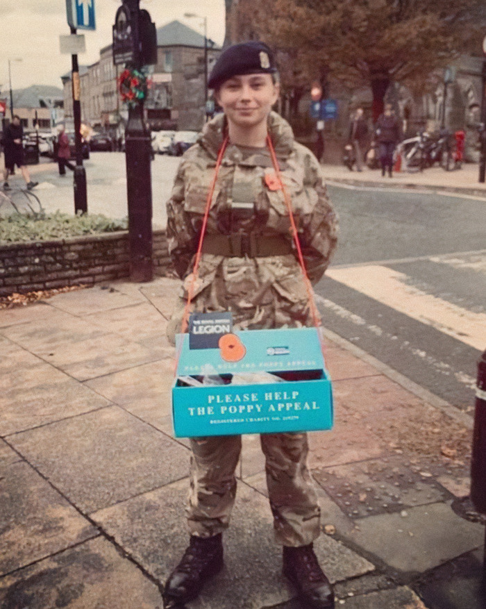 Young soldier in uniform participating in the Poppy Appeal on a city street.