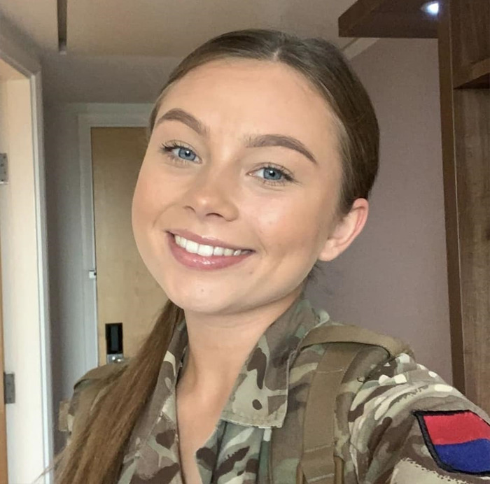 19-year-old soldier in uniform smiling indoors.